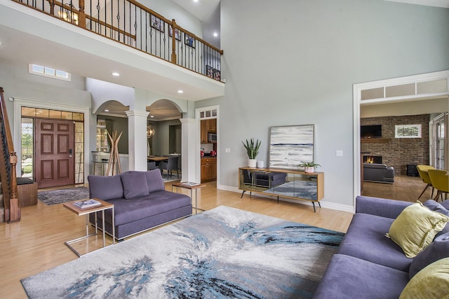 6577 Heron Ct, Ann Arbor, MI 48103 - living area featuring ornate columns, a high ceiling, arched walkways, wood finished floors, and a large fireplace