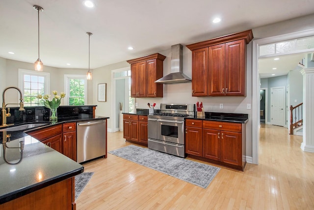 6577 Heron Ct, Ann Arbor, MI 48103 - kitchen featuring wall chimney range hood, appliances with stainless steel finishes, dark countertops, light wood-style flooring, and pendant lighting