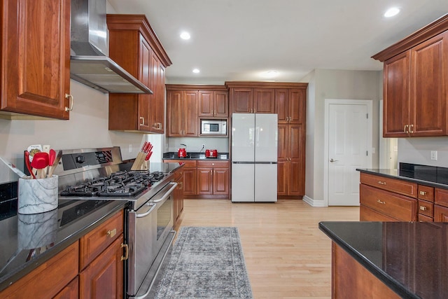 6577 Heron Ct, Ann Arbor, MI 48103 - kitchen featuring stainless steel appliances, wall chimney range hood, light wood finished floors, dark stone countertops, and recessed lighting