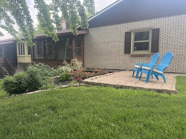 7337 Pine Grove Dr, Jenison, MI 49428 - rear view of property featuring a sunroom, brick siding, a patio area, and a yard
