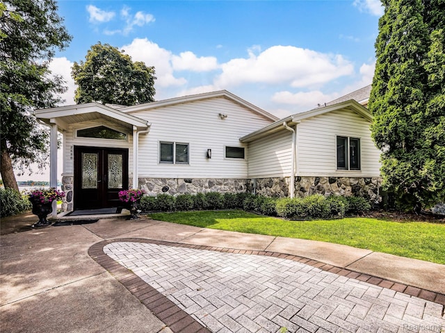 7660 Barnsbury Dr, West Bloomfield, MI 48324 - view of front of house with french doors, stone siding, and a front yard