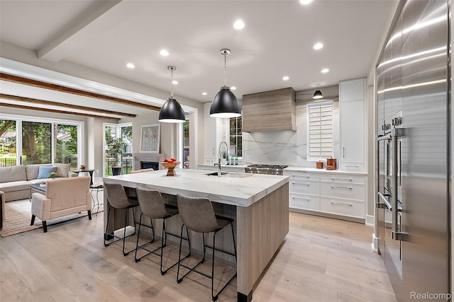 345 Kimberly St, Birmingham, MI 48009 - kitchen with modern cabinets, custom range hood, a center island with sink, light wood-style floors, and a kitchen breakfast bar