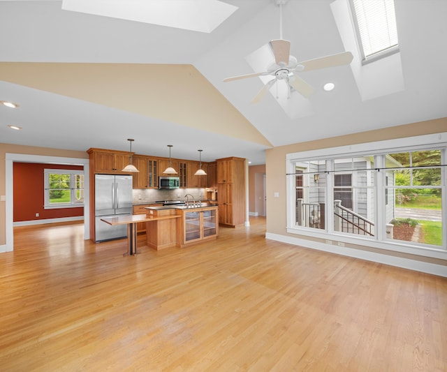 4641 Wylie Rd, Dexter, MI 48130 - kitchen with stainless steel appliances, a skylight, brown cabinetry, high vaulted ceiling, and a kitchen bar
