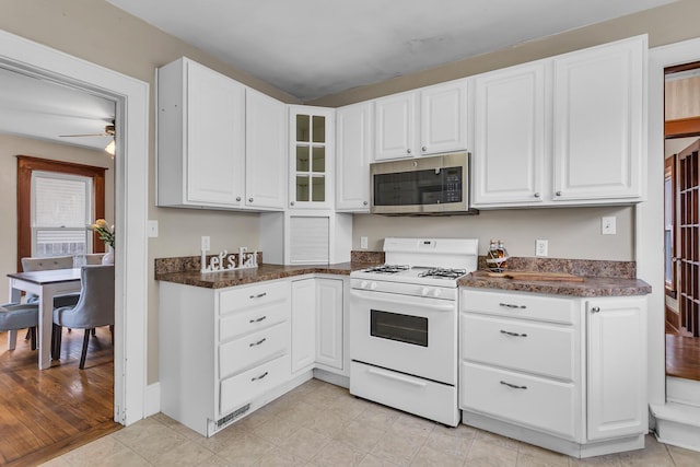 1218 Forest Ave, Jackson, MI 49201 - kitchen featuring stainless steel microwave, white gas stove, white cabinets, and ceiling fan