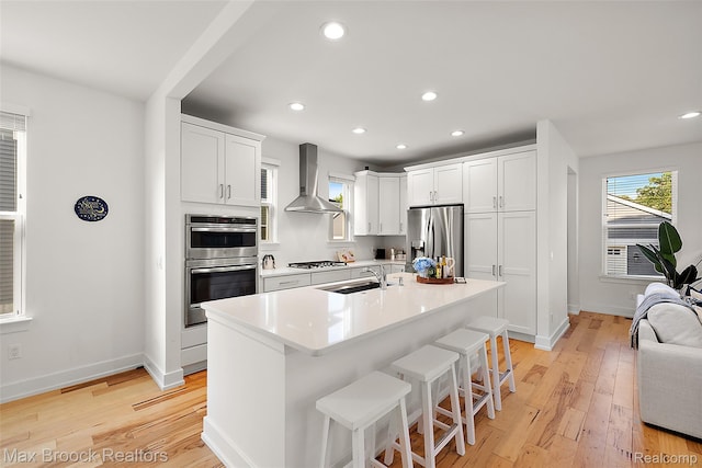 4260 Kent Rd, Royal Oak, MI 48073 - kitchen featuring wall chimney exhaust hood, stainless steel appliances, a kitchen breakfast bar, light wood-type flooring, and recessed lighting