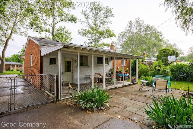 24745 Ross Dr, Redford, MI 48239 - rear view of house featuring brick siding, a gate, a chimney, and a patio