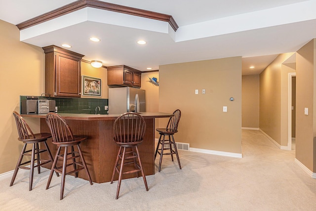 10310 E Rivershore Dr SE, Alto, MI 49302 - kitchen with stainless steel refrigerator with ice dispenser, light carpet, a peninsula, decorative backsplash, and a breakfast bar