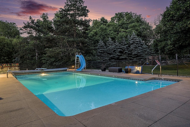 10310 E Rivershore Dr SE, Alto, MI 49302 - pool at dusk with a water slide, a patio area, a diving board, and a playground