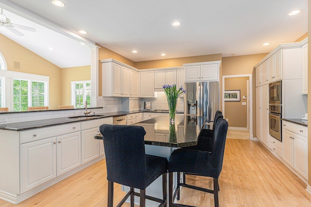 10310 E Rivershore Dr SE, Alto, MI 49302 - kitchen with appliances with stainless steel finishes, light wood finished floors, tasteful backsplash, a center island, and white cabinetry