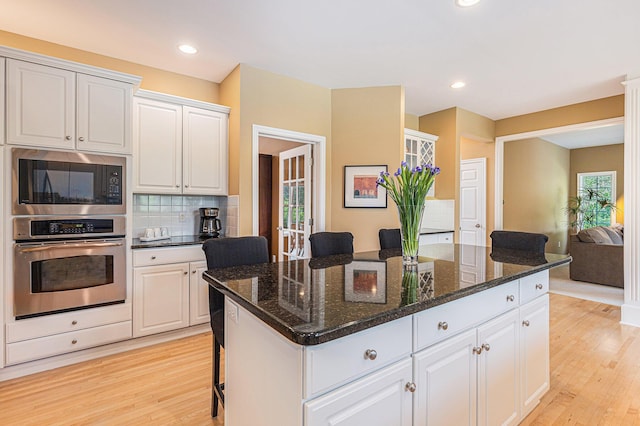 10310 E Rivershore Dr SE, Alto, MI 49302 - kitchen with oven, built in microwave, light wood finished floors, a kitchen bar, and recessed lighting