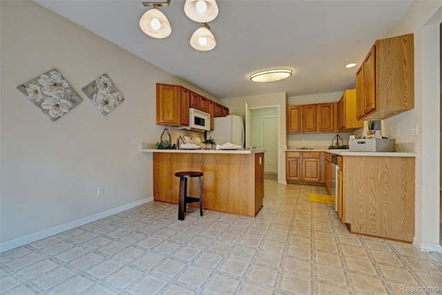 333 Sherman Ct, Ortonville, MI 48462 - kitchen with white appliances, a peninsula, light countertops, a breakfast bar, and brown cabinets