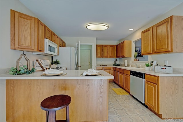 333 Sherman Ct, Ortonville, MI 48462 - kitchen with white appliances, a peninsula, light countertops, a kitchen bar, and light floors