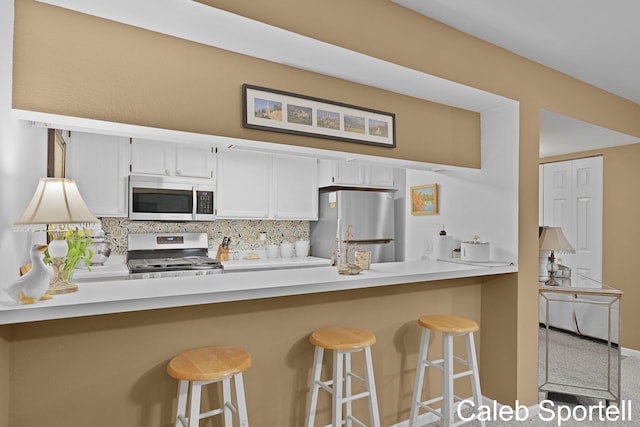 3360 Pine Meadow Dr SE Unit 202, Kentwood, MI 49512 - kitchen with stainless steel microwave, range, freestanding refrigerator, a peninsula, and decorative backsplash