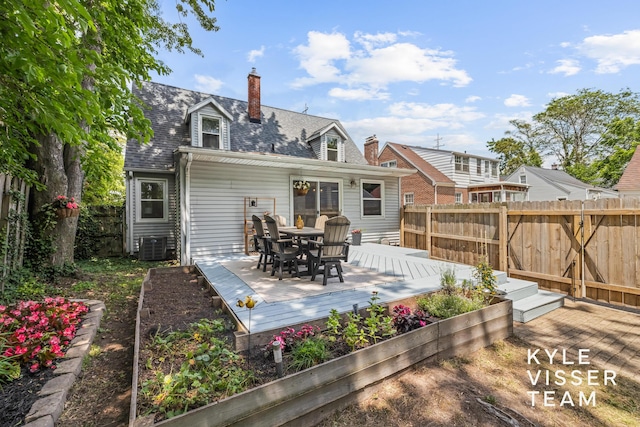 1624 Boston St SE, Grand Rapids, MI 49506 - rear view of house with a fenced backyard, outdoor dining space, a deck, a chimney, and roof with shingles