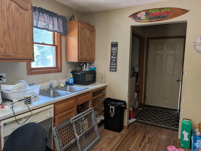 197 E Cedar Rd, Twin Lake, MI 49457 - kitchen featuring dishwasher, black microwave, wood finished floors, light countertops, and brown cabinetry