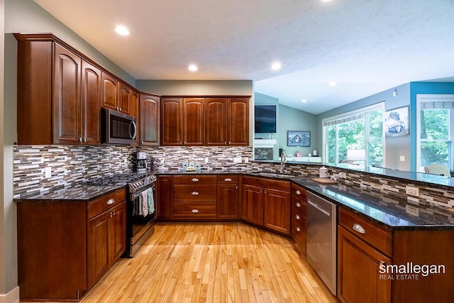 3440 Monterey Hills Dr NE, Grand Rapids, MI 49525 - kitchen featuring stainless steel appliances, light wood-type flooring, dark stone countertops, a peninsula, and backsplash