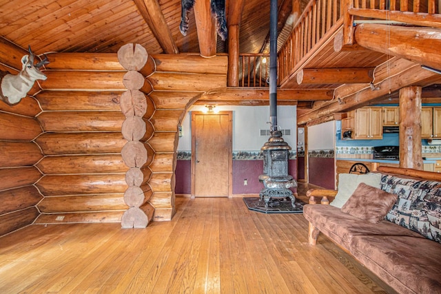 12170 Riethmiller Rd, Grass Lake, MI 49240 - living area with a wood stove, light wood-style floors, log walls, a wood ceiling with exposed beams, and arched walkways