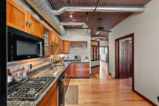 333 State St Unit 5, Saint Joseph, MI 49085 - kitchen featuring black appliances, brown cabinetry, dark stone countertops, a ceiling fan, and light wood-type flooring