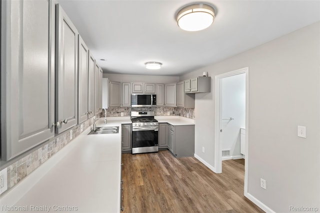 7220 Dodge Ave, Warren, MI 48091 - kitchen with appliances with stainless steel finishes, gray cabinets, decorative backsplash, and wood finished floors
