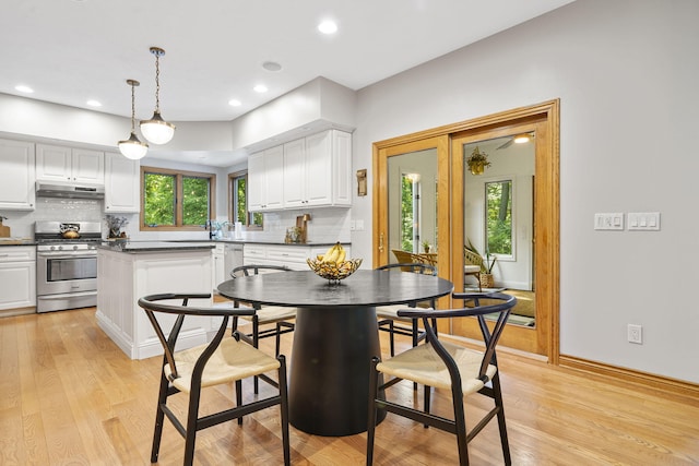 1255 White Pine Dr SW, Grand Rapids, MI 49534 - kitchen with stainless steel range with gas stovetop, under cabinet range hood, dark countertops, white cabinets, and backsplash