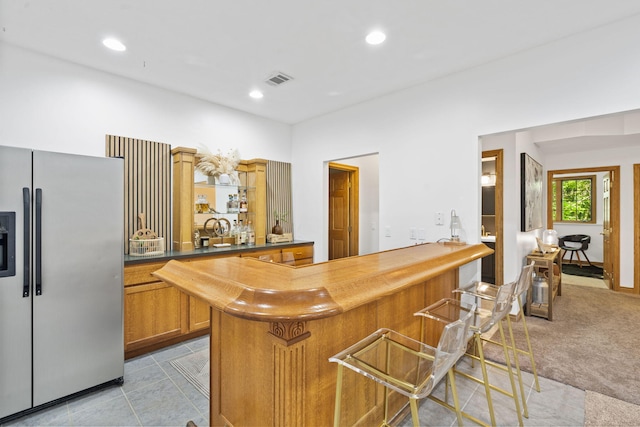 1255 White Pine Dr SW, Grand Rapids, MI 49534 - kitchen featuring stainless steel fridge with ice dispenser, brown cabinetry, a kitchen breakfast bar, recessed lighting, and a peninsula