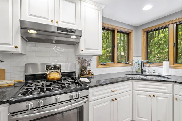 1255 White Pine Dr SW, Grand Rapids, MI 49534 - kitchen with stainless steel gas range oven, under cabinet range hood, white cabinets, backsplash, and dark stone counters