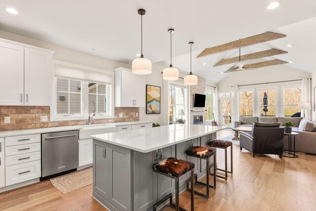 3078 N Spurway Dr, Ann Arbor, MI 48105 - kitchen featuring stainless steel dishwasher, open floor plan, light wood-type flooring, backsplash, and a kitchen island