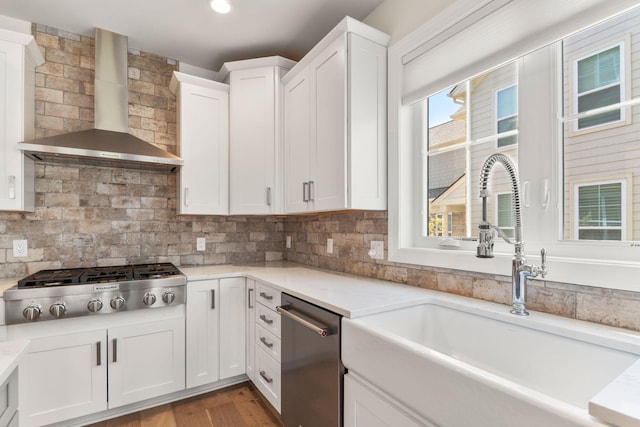 3078 N Spurway Dr, Ann Arbor, MI 48105 - kitchen featuring wall chimney range hood, appliances with stainless steel finishes, white cabinets, backsplash, and wood finished floors