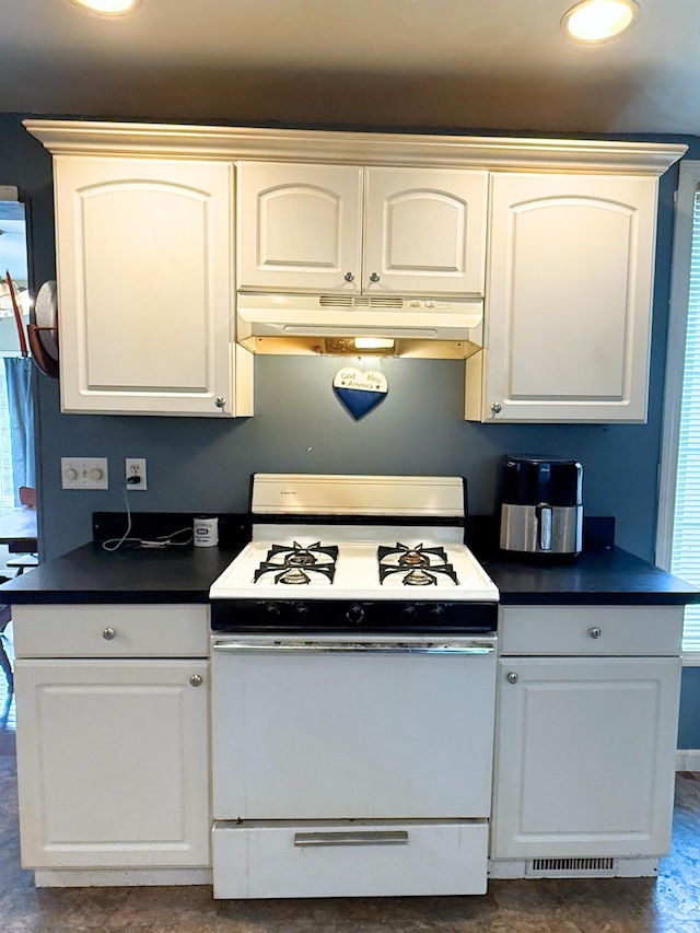 512 E Main St, Owosso, MI 48867 - kitchen with white gas range oven, under cabinet range hood, dark countertops, and white cabinetry