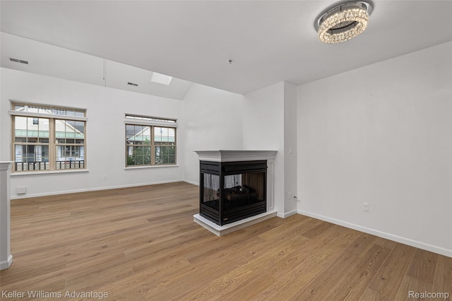 438 Old Pine Way, Walled Lake, MI 48390 - unfurnished living room featuring wood finished floors, a multi sided fireplace, and a chandelier