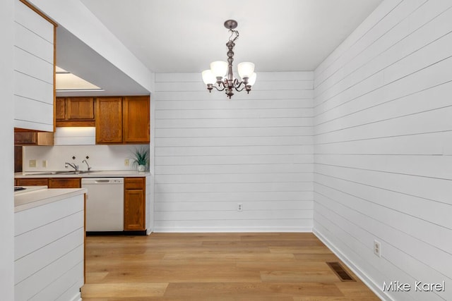 666 Waterview Ct SW, Grandville, MI 49418 - kitchen with white dishwasher, a chandelier, brown cabinetry, light countertops, and light wood finished floors