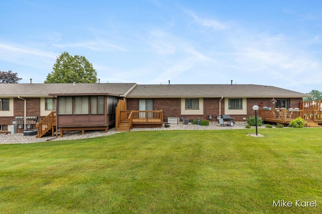 666 Waterview Ct SW, Grandville, MI 49418 - rear view of property featuring a wooden deck, a sunroom, brick siding, and a lawn