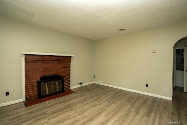 21890 Sharkey St, Clinton Township, MI 48035 - unfurnished living room with wood finished floors, arched walkways, a fireplace, and a textured ceiling