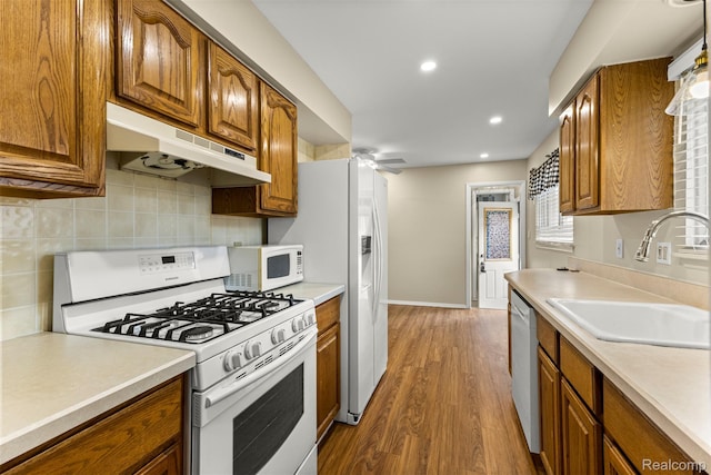 7420 Colonial St, Dearborn Heights, MI 48127 - kitchen with white appliances, under cabinet range hood, brown cabinetry, wood finished floors, and recessed lighting