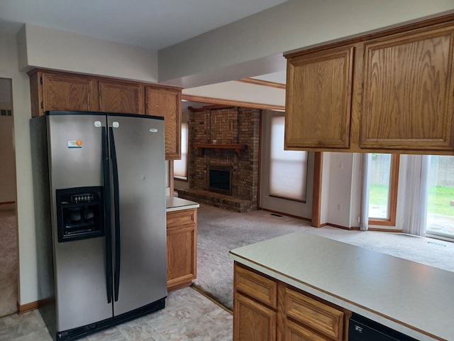 46817 Barbara Dr, Macomb, MI 48044 - kitchen featuring stainless steel fridge with ice dispenser, light colored carpet, a brick fireplace, light countertops, and brown cabinetry