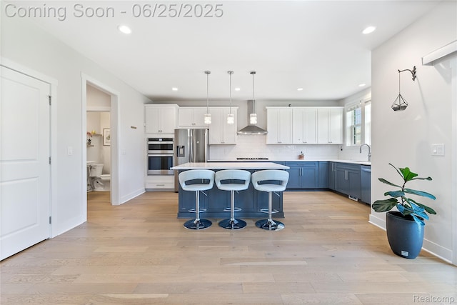 51008 Woodford Dr, Canton, MI 48188 - kitchen featuring wall chimney exhaust hood, stainless steel appliances, blue cabinets, light wood-type flooring, and recessed lighting