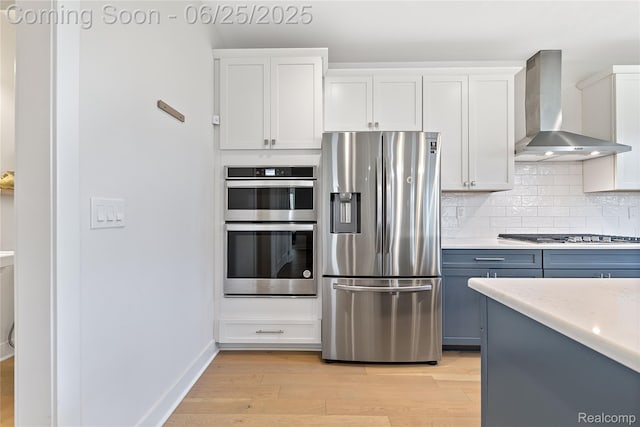 51008 Woodford Dr, Canton, MI 48188 - kitchen featuring appliances with stainless steel finishes, wall chimney exhaust hood, light wood-style floors, tasteful backsplash, and light countertops