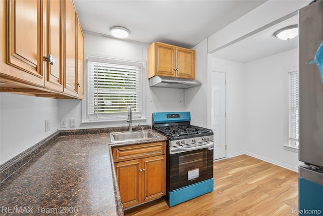 26389 Annapolis St, Dearborn Heights, MI 48125 - kitchen featuring stainless steel range with gas cooktop, under cabinet range hood, dark countertops, light wood-style flooring, and brown cabinets