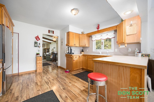 11829 Hoskins Ave NE, Cedar Springs, MI 49319 - kitchen featuring freestanding refrigerator, a peninsula, a kitchen breakfast bar, light wood-type flooring, and light countertops