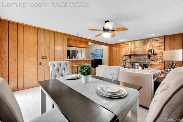 8798 Lozen Dr, Sterling Heights, MI 48313 - dining space featuring ceiling fan, wooden walls, a fireplace, a textured ceiling, and light colored carpet