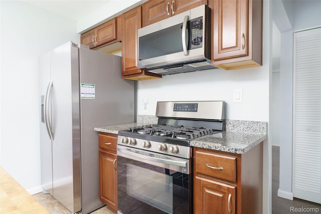 1478 Desoto Ave, Ypsilanti, MI 48198 - kitchen with stainless steel appliances, brown cabinetry, and light stone countertops