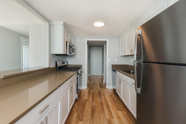 3320 Spinnaker Ln Unit 16D, Detroit, MI 48207 - kitchen featuring appliances with stainless steel finishes, white cabinetry, dark countertops, and light wood finished floors