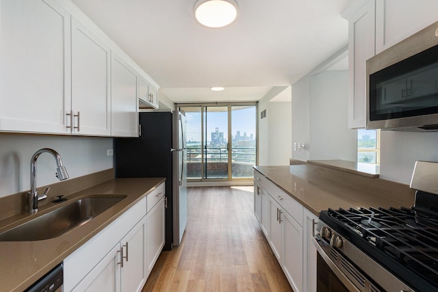 3320 Spinnaker Ln Unit 16D, Detroit, MI 48207 - kitchen with stainless steel appliances, plenty of natural light, white cabinets, and light wood-style flooring