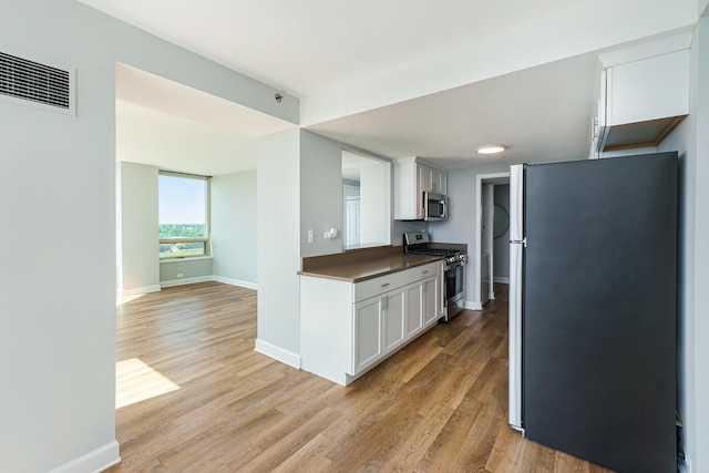 3320 Spinnaker Ln Unit 16D, Detroit, MI 48207 - kitchen with stainless steel appliances, light wood-style flooring, dark countertops, and white cabinets