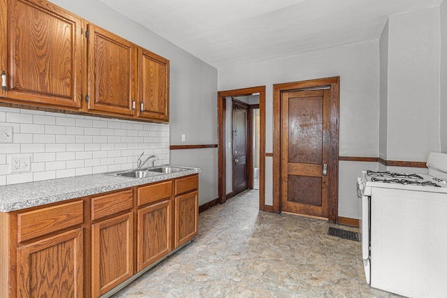941 Mcreynolds Ave NW, Grand Rapids, MI 49504 - kitchen featuring white gas range oven, brown cabinets, decorative backsplash, and light countertops