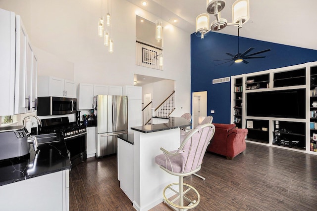 1156 N Bridge St, Linden, MI 48451 - kitchen featuring stainless steel appliances, high vaulted ceiling, dark countertops, dark wood-type flooring, and white cabinetry