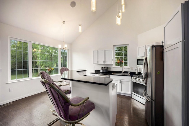 1156 N Bridge St, Linden, MI 48451 - kitchen with stainless steel appliances, dark countertops, white cabinetry, a chandelier, and a kitchen breakfast bar