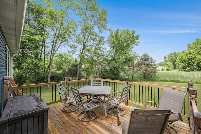 1156 N Bridge St, Linden, MI 48451 - wooden deck with outdoor dining area, a lawn, and view of scattered trees