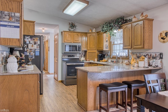 845 Riverlane Dr, Owosso, MI 48867 - kitchen featuring stainless steel appliances, vaulted ceiling, a peninsula, a breakfast bar, and light wood-style floors