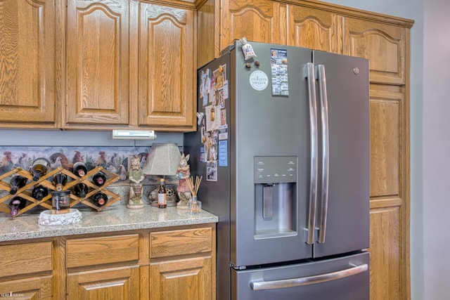 845 Riverlane Dr, Owosso, MI 48867 - kitchen with stainless steel fridge with ice dispenser, light stone counters, and brown cabinets